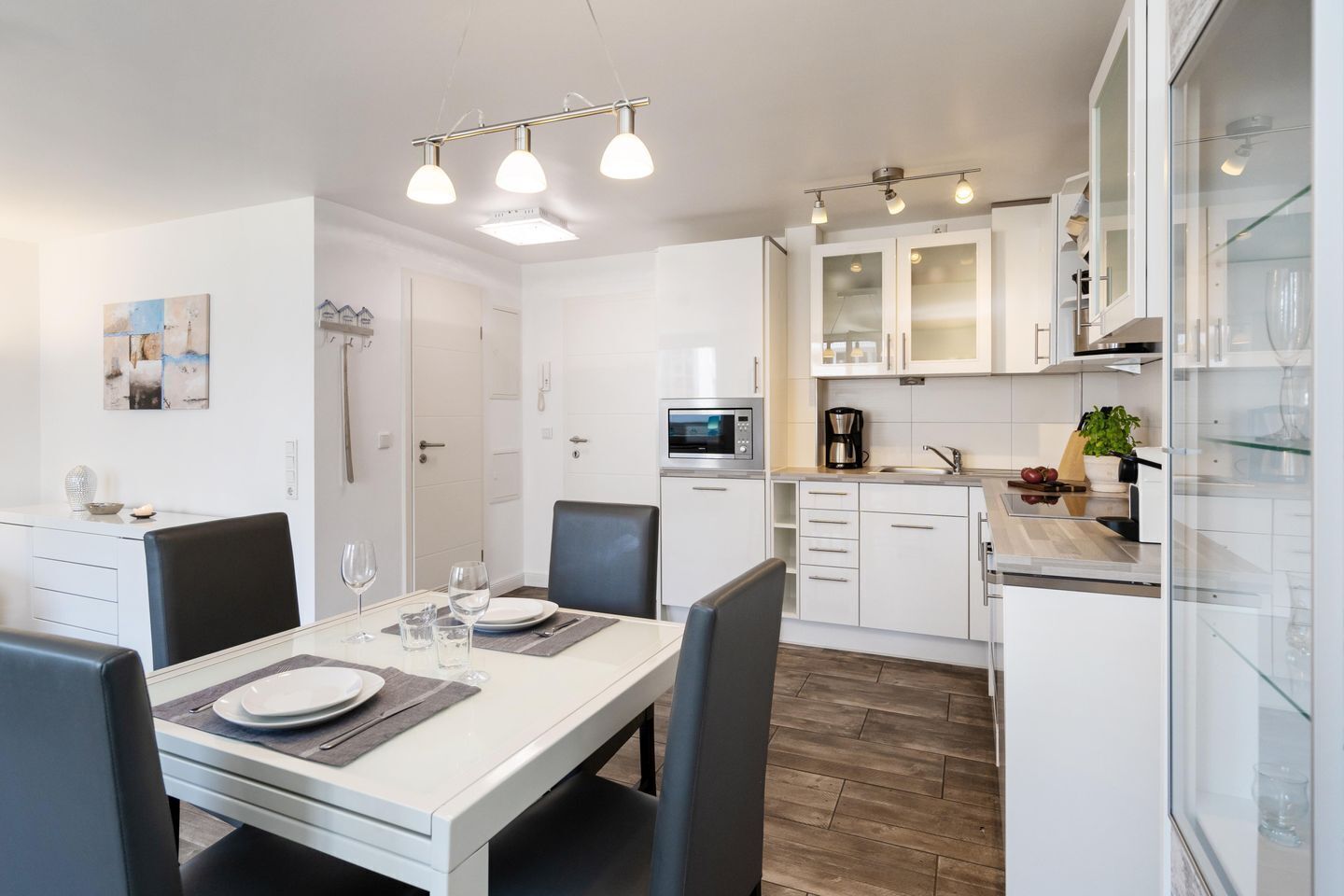 A modern kitchen with white cabinets, a microwave, and a coffee maker.