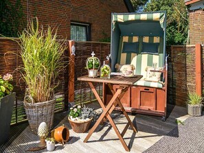 A cozy outdoor seating area with a wooden table, wicker baskets, and potted plants.
