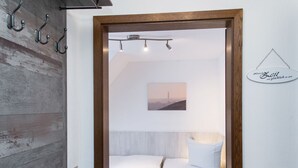 Habitación de hotel con pared de madera, cama con edredón blanco, mesita de noche con lámpara y un cuadro en la pared.