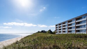 Un hotel frente a la playa con diseño moderno, con varios balcones y vistas al mar.