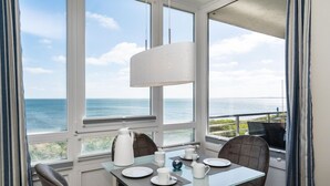 Comedor con una mesa dispuesta para dos personas, con vistas a la costa.