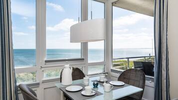 Een eethoek met een tafel voor twee, met uitzicht op de kust.