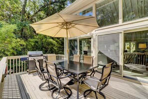 An outdoor deck with a table and chairs, a grill, and a large umbrella. - 7 Seaside Sparrow at The Sea Pines Resort (Hilton Head Island)