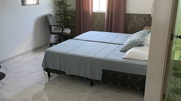 Een slaapkamer met een bed, een stoel, een potplant en een poster aan de muur.