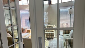A room with a wooden ceiling, a large window, and a view of a patio area with furniture. - Exclusive Lakefront Home Retreat w/Baby Grand Piano for Family FLX Fun & Friends (Ovid)