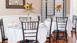 A dining area with round tables, black chairs, and white tablecloths. - Liberty Hall Bed and Breakfast (Pendleton)
