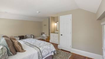 Un dormitorio con una cama grande, un aparador, un tocador y una puerta.