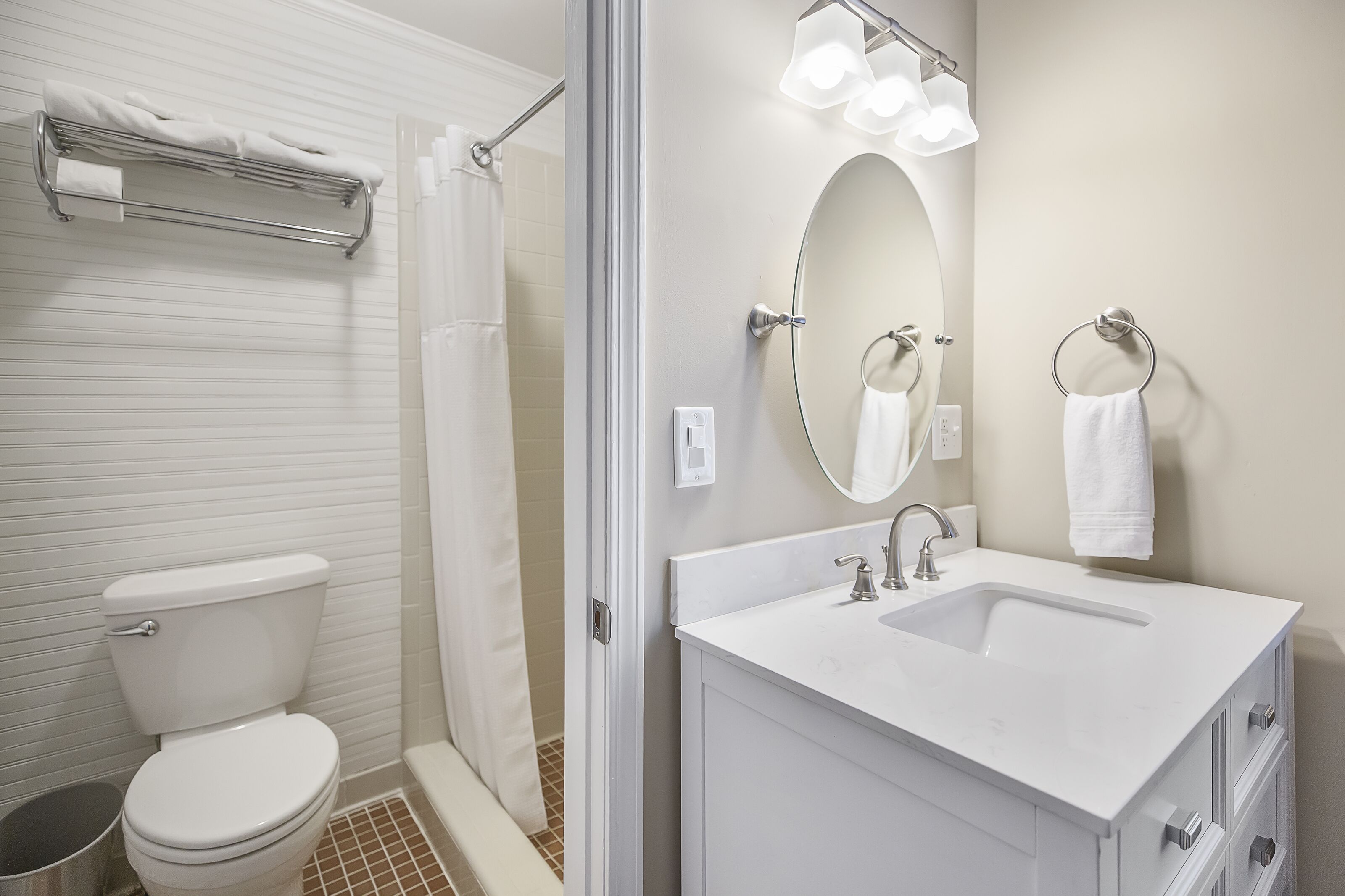 Un baño con inodoro, ducha, lavamanos y espejo.