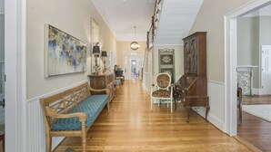 A hallway with a wooden bench, a chair, a cabinet, and a painting on the wall. - Liberty Hall Bed and Breakfast (Pendleton)