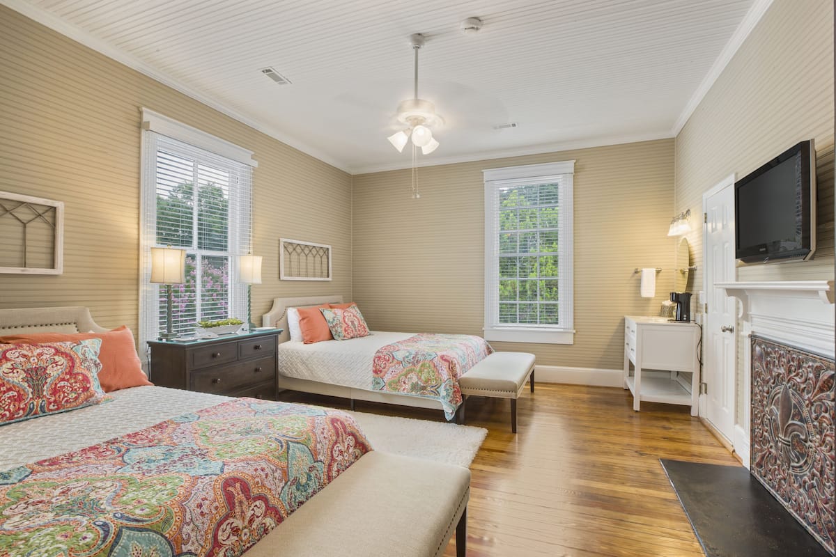 A bedroom with two beds, a TV, and a fireplace.