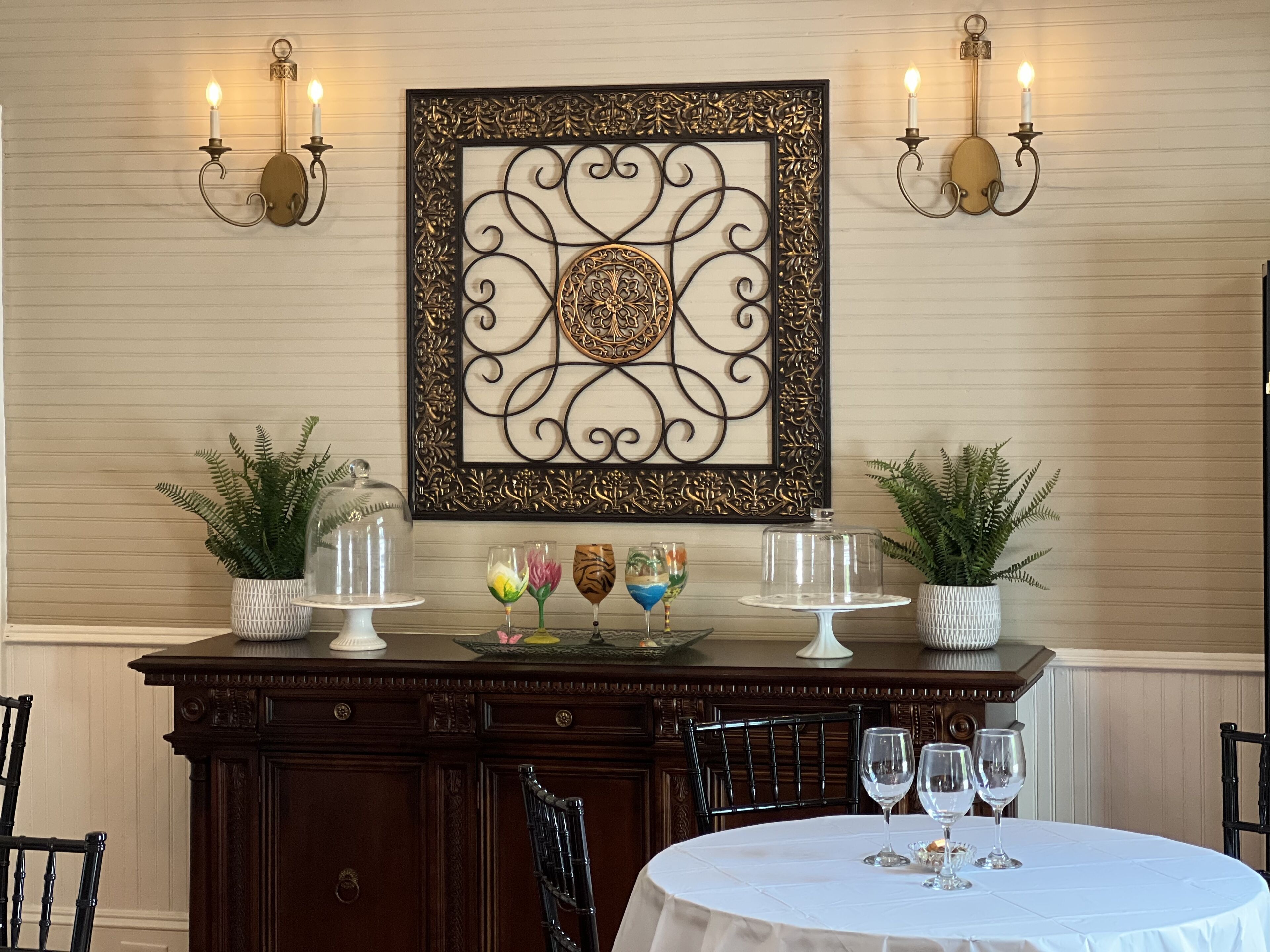 Comedor con una mesa dispuesta para cuatro, un adorno en la pared y dos apliques con velas.