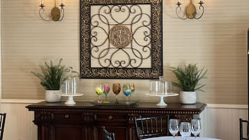 Comedor con una mesa dispuesta para cuatro, un adorno en la pared y dos apliques con velas.