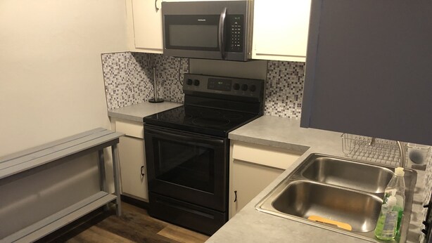 A compact kitchen with a microwave, stove, oven, and a sink with a dish soap bottle. - Last minute opening for Cheyenne Frontier Days! (Cheyenne)