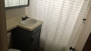 A small bathroom with a white sink, dark cabinet, and a white toilet. - Last minute opening for Cheyenne Frontier Days! (Cheyenne)