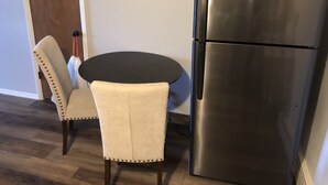 A kitchen with a stainless steel refrigerator, a round black table, and two upholstered chairs. - Last minute opening for Cheyenne Frontier Days! (Cheyenne)