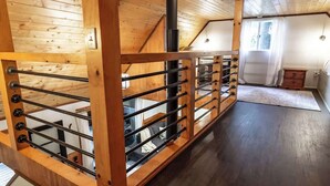 Una escalera de madera con barandillas de metal que lleva a una zona superior con una chimenea.