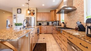 A modern kitchen with granite countertops, stainless steel appliances, wooden cabinets, and a brick backsplash. - Luxury Resort Style, Heated Pool, 10 Mins to Gulf Mexico Beaches (Bradenton)