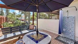 A covered outdoor seating area with a mosaic-tiled table, a bench, and a shower area with a tiled wall. - Luxury Resort Style, Heated Pool, 10 Mins to Gulf Mexico Beaches (Bradenton)