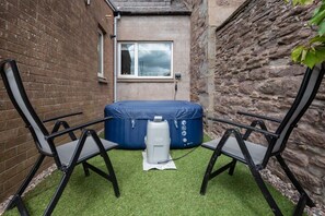A small outdoor seating area with two black chairs and a blue inflatable hot tub. - Scotston Villa - 5 bedroom house with large private back garden & hot tub (Forfar)