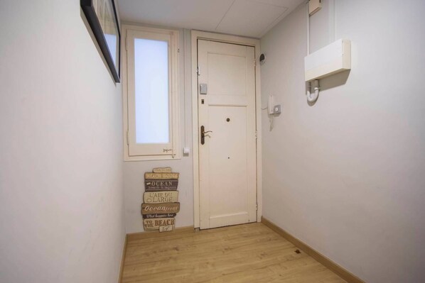 A narrow hallway with a wooden floor, a white door, and a small window. - 23par1007 Enjoyable 3 bedroom apartment (Barcelona)