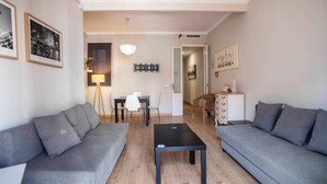 Una sala de estar moderna con dos sofás grises, una mesa de centro negra y un comedor con una mesa y sillas.