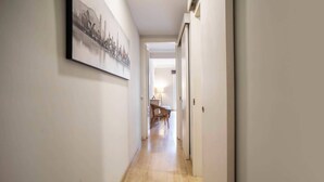 Un pasillo estrecho con suelo de madera, una obra de arte urbana enmarcada en la pared izquierda y una puerta a la derecha.