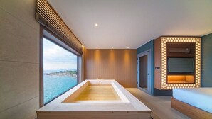 A modern bathroom with a large bathtub, a wooden vanity, and a TV mounted on the wall. - Yeonhwamoon Hotel Yeongdeok (Yeongdeok)