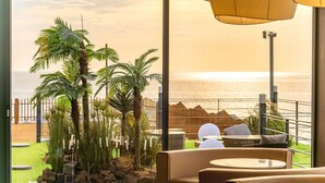 A balcony with a view of the sea, featuring palm trees and outdoor seating. - Yeonhwamoon Hotel Yeongdeok (Yeongdeok)
