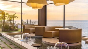 A modern indoor pool area with seating and a view of the ocean. - Yeonhwamoon Hotel Yeongdeok (Yeongdeok)