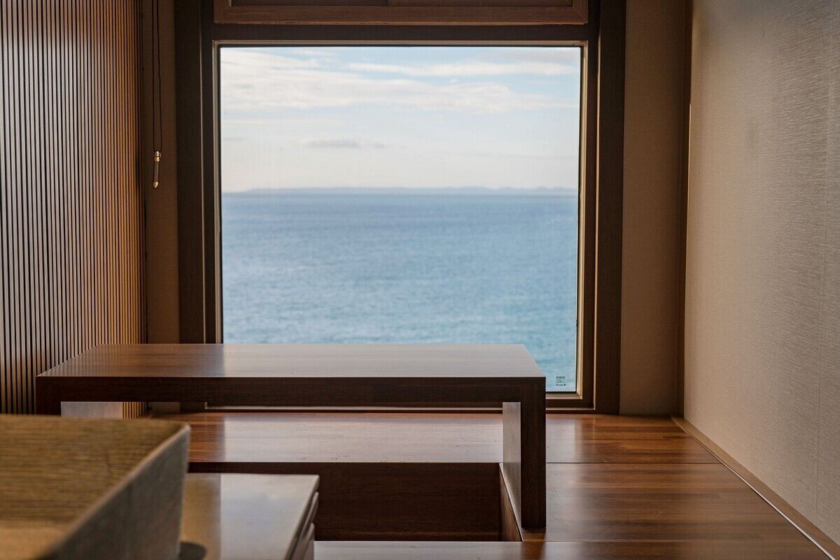 A modern room with a large window offering a view of the sea.
