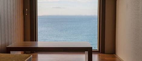 A modern room with a large window offering a view of the sea.