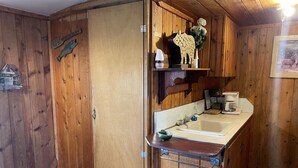 A wooden cabin interior with a kitchenette, a sink, and a small countertop. - Relaxing Cabin in the heart of Red Feather Lakes!! (Red Feather Lakes)