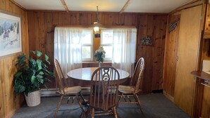 A wooden dining room with a round table and four chairs, a potted plant, and a painting on the wall. - Relaxing Cabin in the heart of Red Feather Lakes!! (Red Feather Lakes)