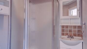 A bathroom with a glass-enclosed shower, a sink, and a mirror above it.