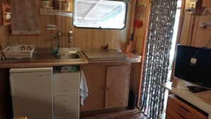 Uma cozinha compacta com armários de madeira, uma pia, uma geladeira pequena e uma janela com vista.
