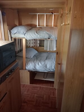 Een compact interieur van een camper, met een kitchenette, een onderkastelenbed en een bed boven de cabine.