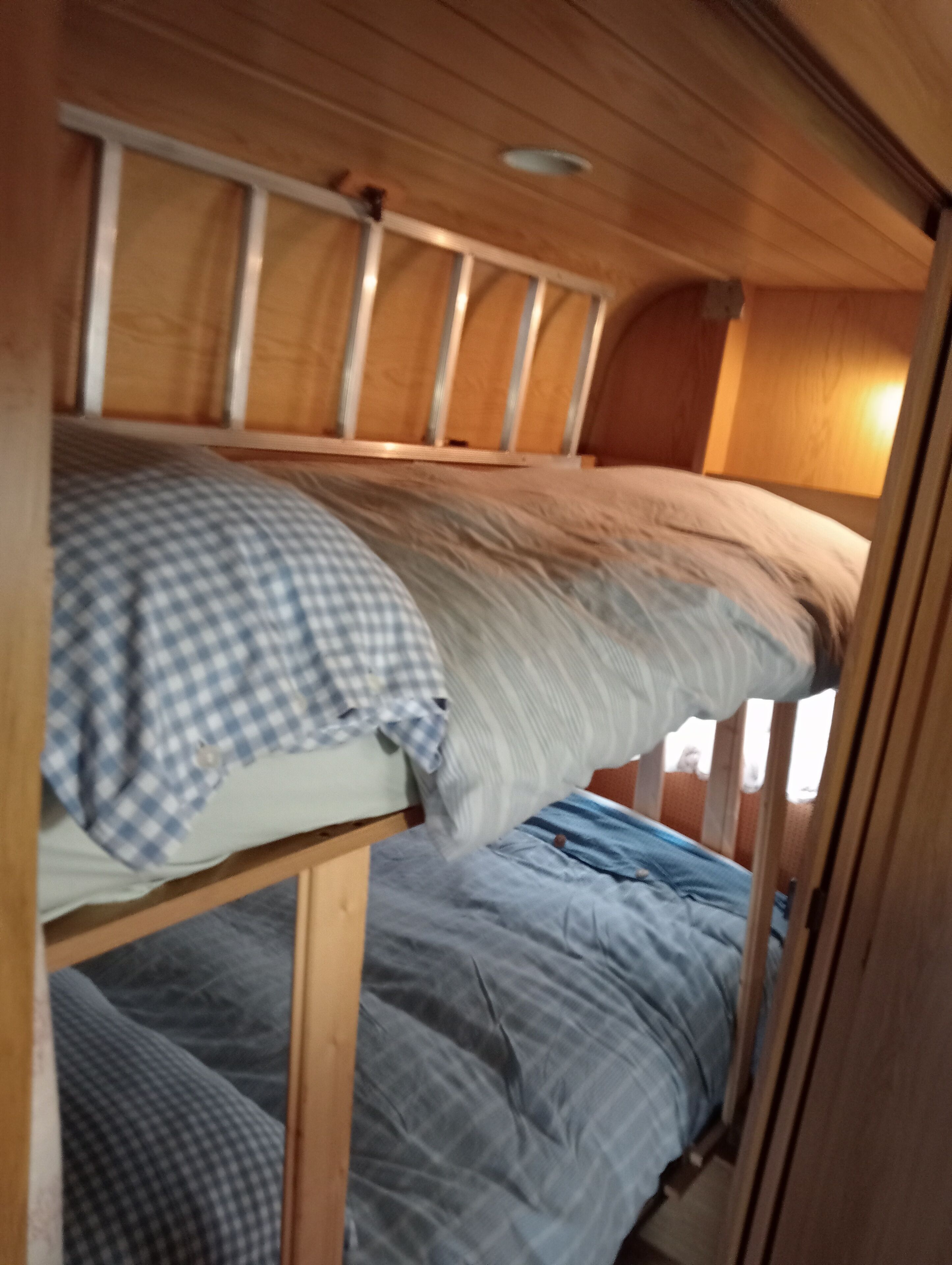Ein Stockbett mit karierter und schlichter Decke.