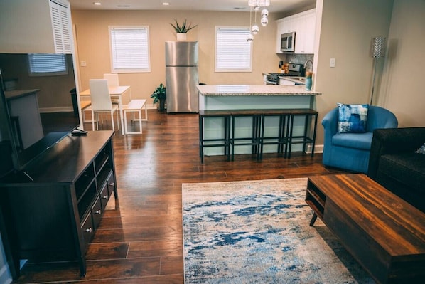 Un salon moderne avec un meuble de rangement en bois foncé pour les appareils multimédias, un canapé bleu et un tapis à motifs.
