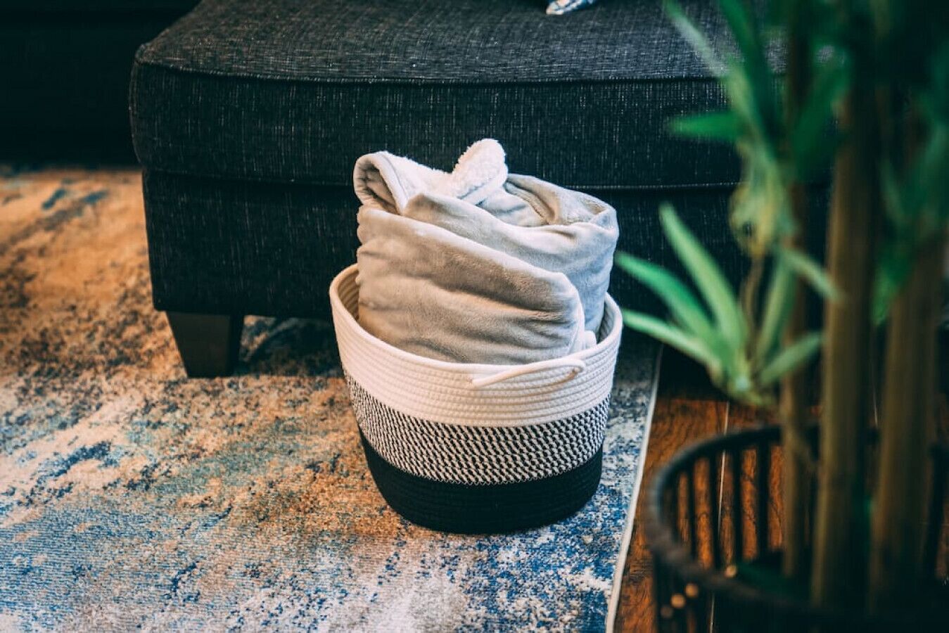 A basket with folded towels on a textured rug.