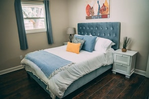 Une chambre à coucher avec un lit, une table de chevet, une lampe et un tableau au mur.