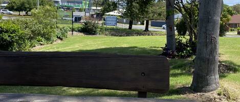 Un banc en bois dans un parc, avec des arbres et une pelouse.
