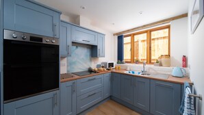 Una cucina moderna con mobili grigi, forno integrato e un'ampia finestra che offre luce naturale.