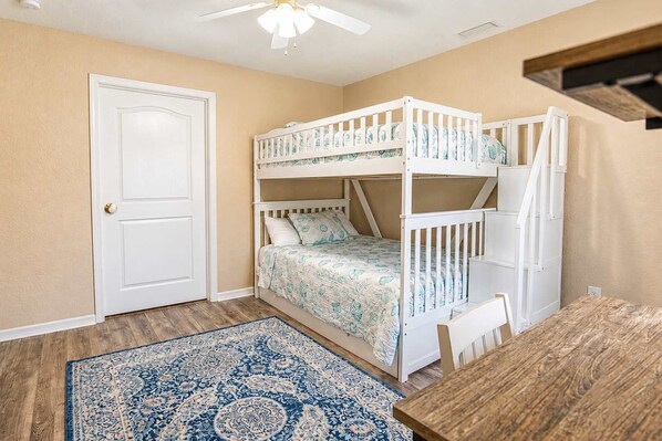 A room with a bunk bed, a door, a patterned rug, and a table. - Gulfstream Villa | Heated Pool + Dog Friendly (Englewood)