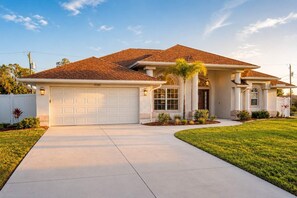 A single-story house with a garage, a well-maintained lawn, and a clear sky. - Gulfstream Villa | Heated Pool + Dog Friendly (Englewood)