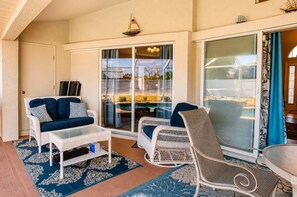 A covered patio area with a white wicker sofa, a wicker chair, and a glass coffee table. - Gulfstream Villa | Heated Pool + Dog Friendly (Englewood)