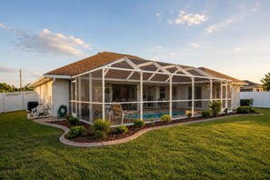 A house with a covered patio, a swimming pool, and a fenced yard. - Gulfstream Villa | Heated Pool + Dog Friendly (Englewood)