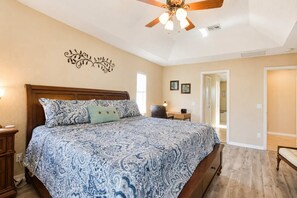 A bedroom with a large bed, a desk, a chair, and a ceiling fan. - Gulfstream Villa | Heated Pool + Dog Friendly (Englewood)