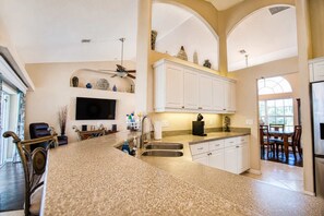 A kitchen with a granite countertop, white cabinetry, and a ceiling fan. - Gulfstream Villa | Heated Pool + Dog Friendly (Englewood)