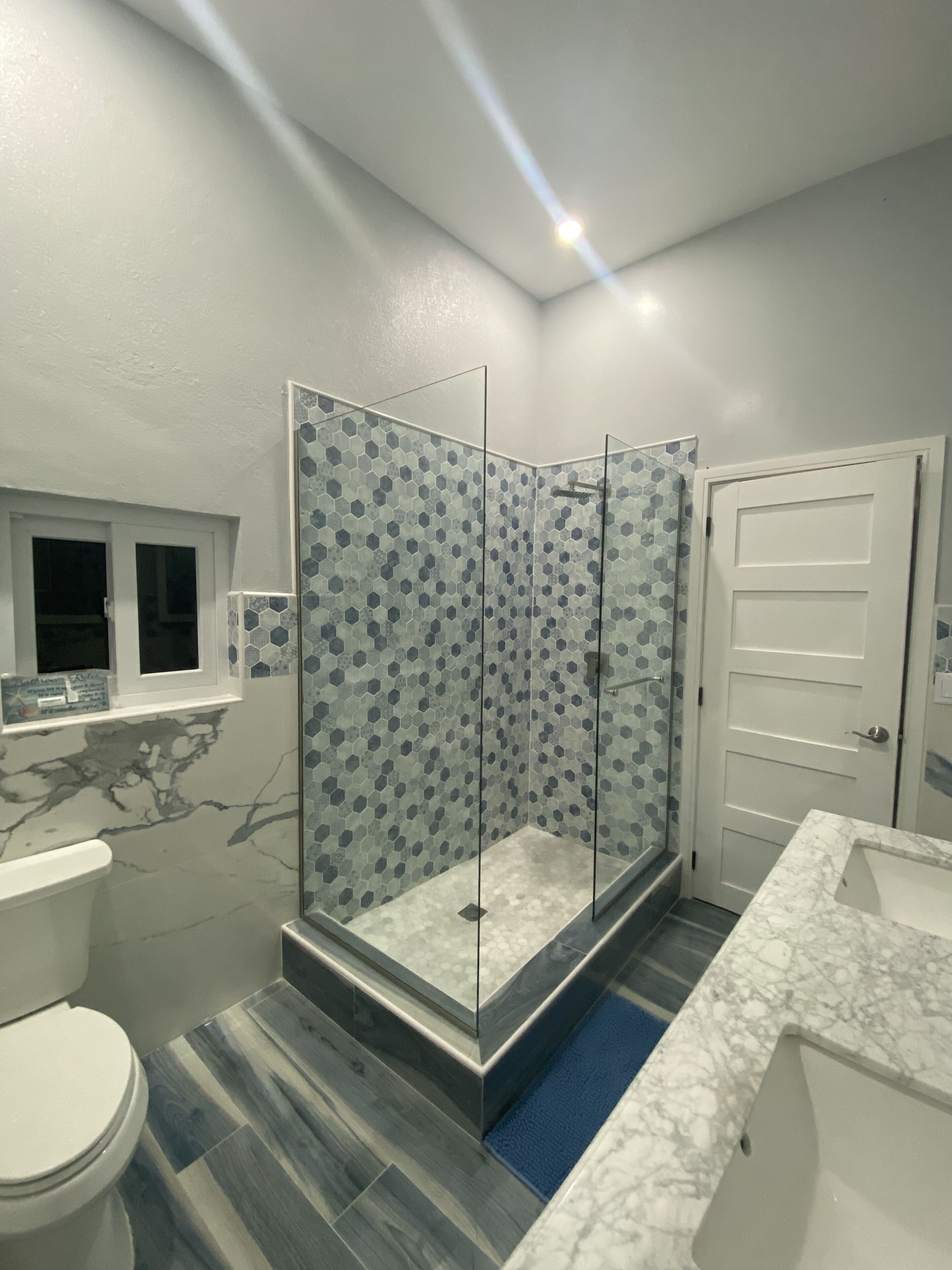 Une salle de bain moderne avec une douche à parois de verre, un lavabo en marbre et des toilettes.