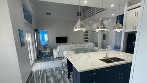 A modern kitchen with a marble island, dark cabinetry, and pendant lighting. - Beautiful modern Harbour house with amazing Sunset Views ! (Black Point, Great Guana Cay)